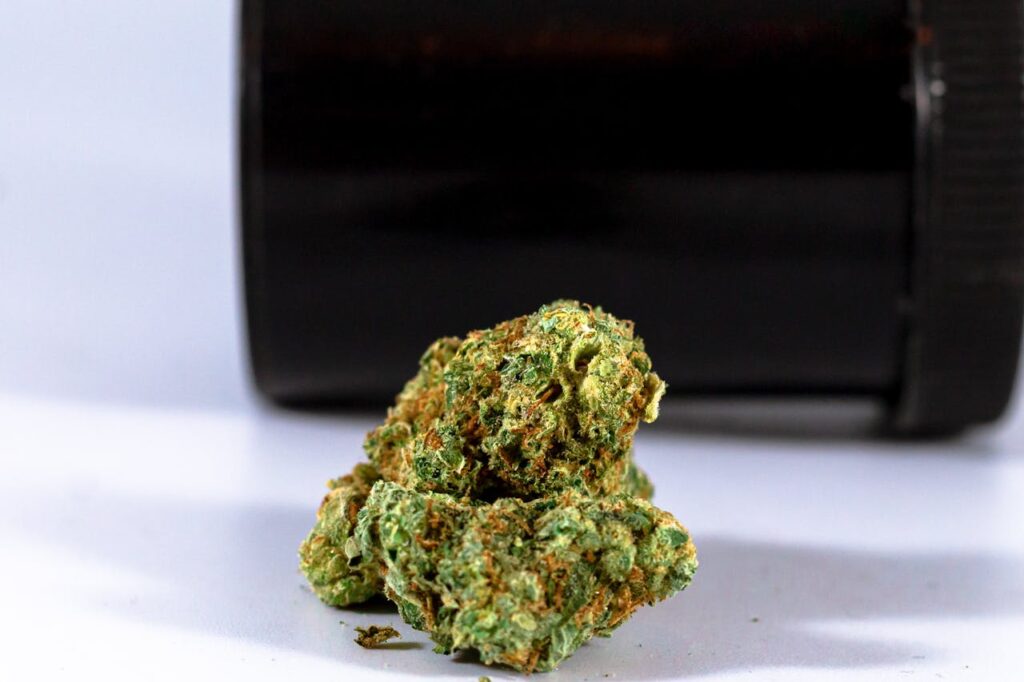Detailed image of cannabis buds on a white surface with a dark container in the background.